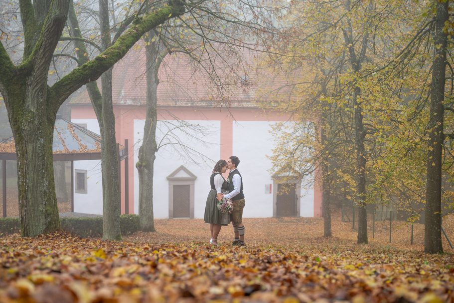 Paar umarmt sich in einem nebligen Herbstwald mit buntem Laub.