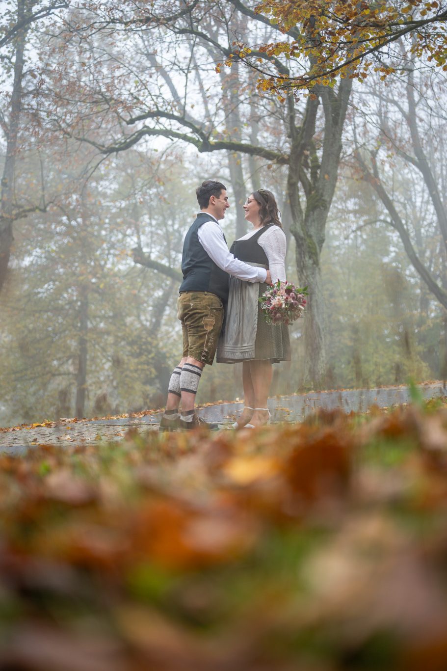 Ein Paar steht sich in einer herbstlichen Landschaft umgeben von buntem Laub gegenüber.