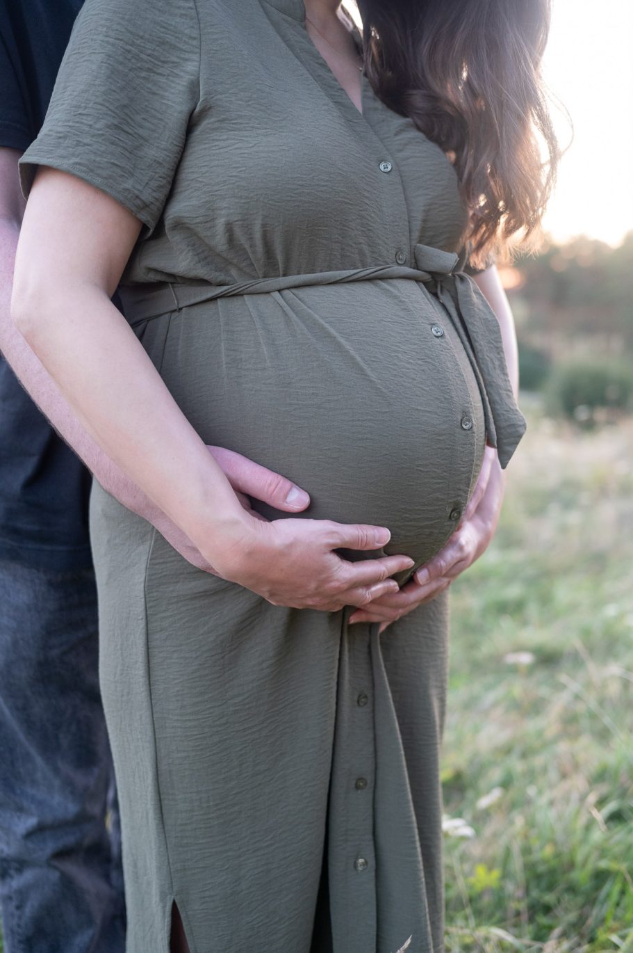 Babybauchshooting - Detailfoto, Mann und Frau nehmen Babybauch in die Hände