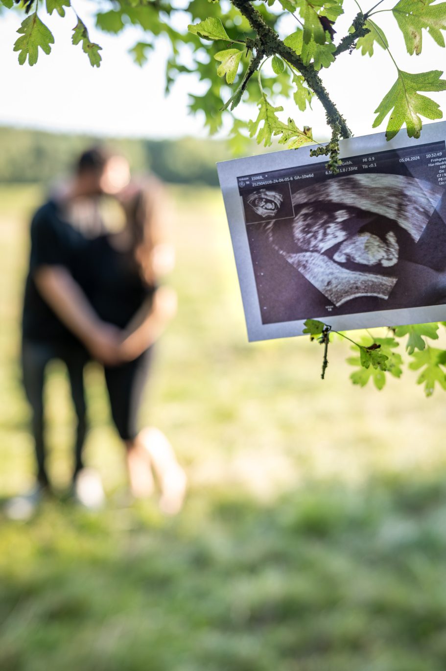 Babybauchshooting - Ultraschallbild im Vordergrund, Paar unscharf im Hintergrund