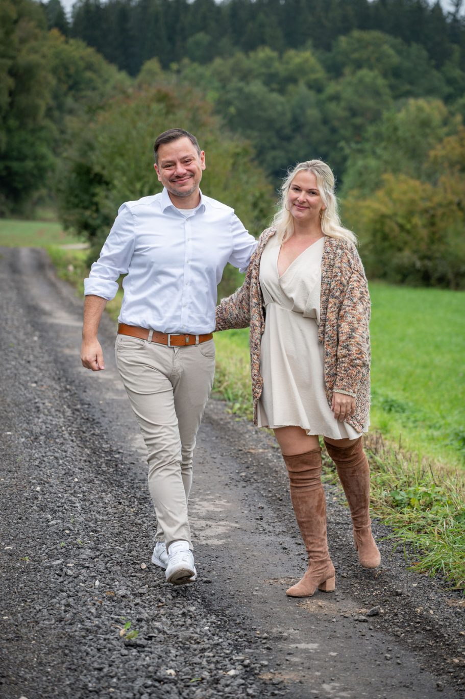 Ein Paar geht entspannt einen Weg entlang, umgeben von grüner Landschaft.